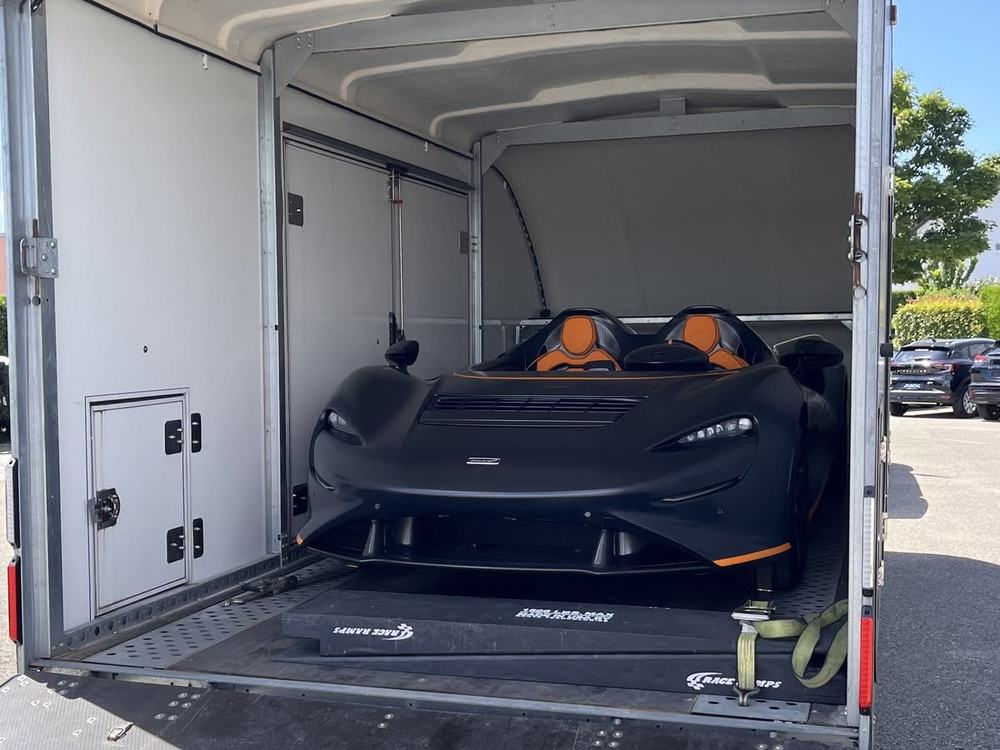Open-top sports car secured in an enclosed trailer